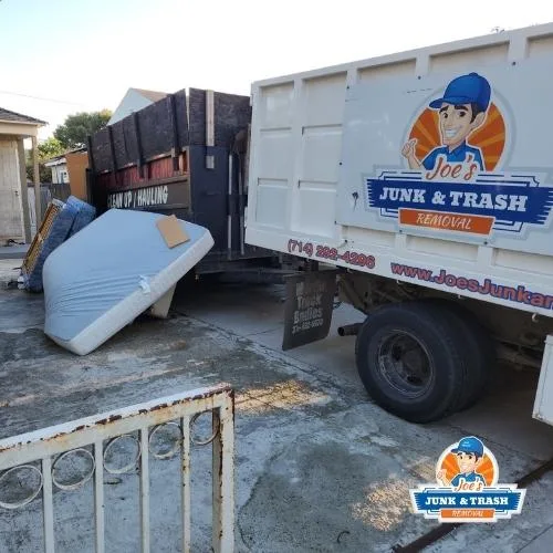 Joe's Junk and Trash Removal truck loaded with an old mattress and junk in Orange County, CA