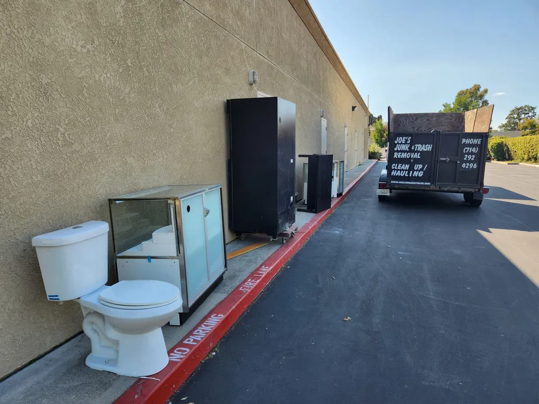 Construction debris removal in Orange, CA, an old toilet and debris beside a Joe's Junk and Trash Removal dumpster